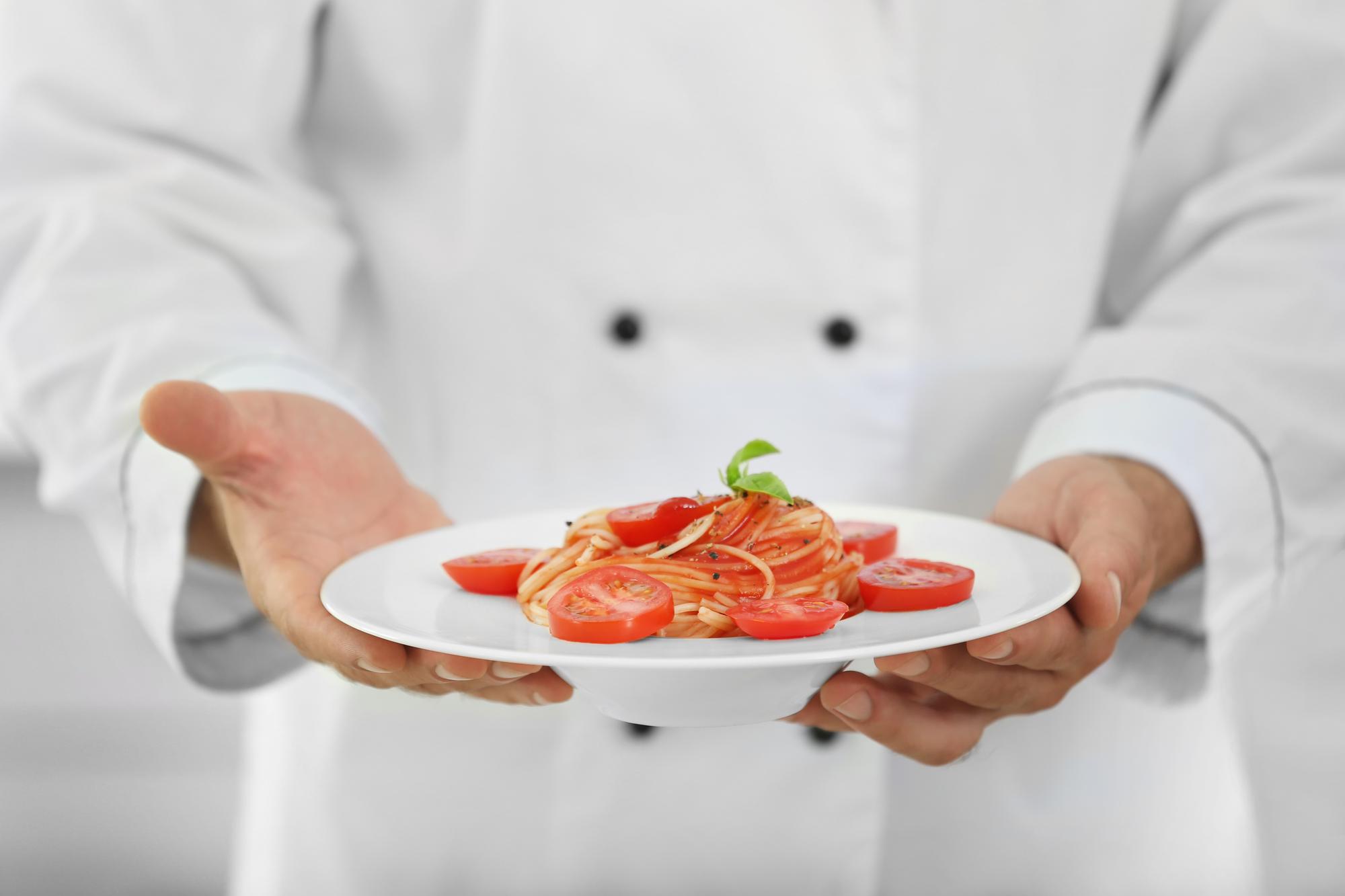 chef plating a dish in a bright kitchen